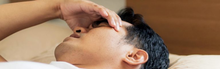 Man laying on bed with headache