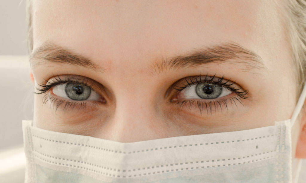 For blog page indicating Infinite Smiles is open. During COVID-19 pandemic, woman wears facial mask for protection.