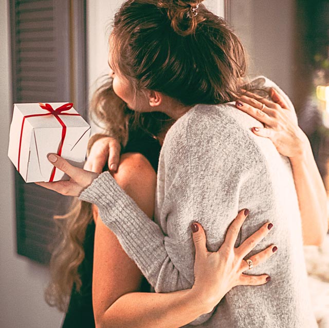 Two women hug after exchanging presents. Giving the gift of great smiles is rewarding.