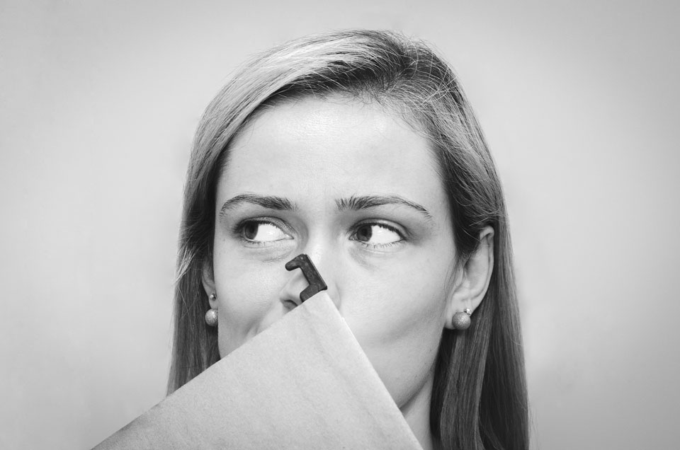 A shy woman looking to replace missing teeth hides her mouth behind a folder.