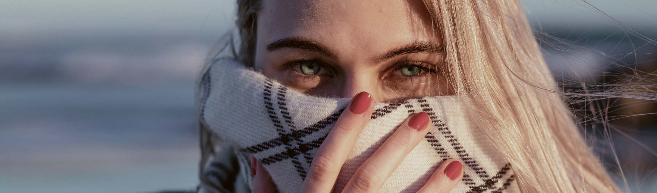 Woman hides her mouth with a scarf. Banner image for replace missing teeth blog post.