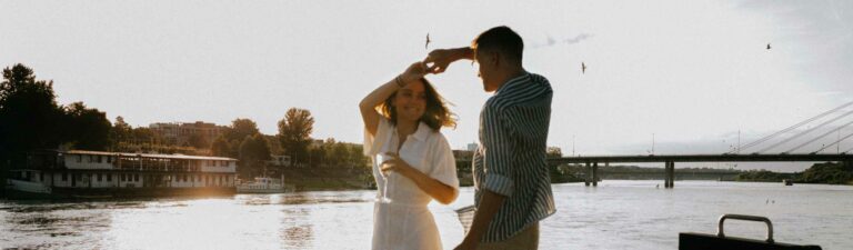 A young couple dances in front of a bay area on a summers day. Image for Destination Dentistry blog post.