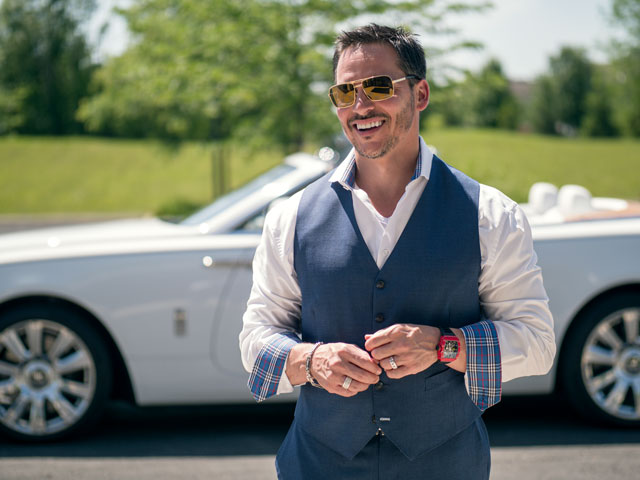 A well dressed man smiles in front of a Rolls-Royce. Image for Destination Dentistry blog post.