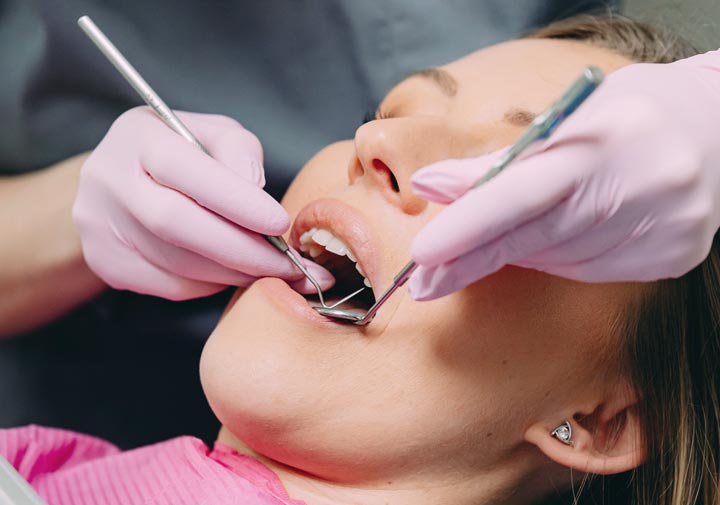 A woman gets her teeth cleaned by a dental hygienist. Image for the debunking dental myths blog post