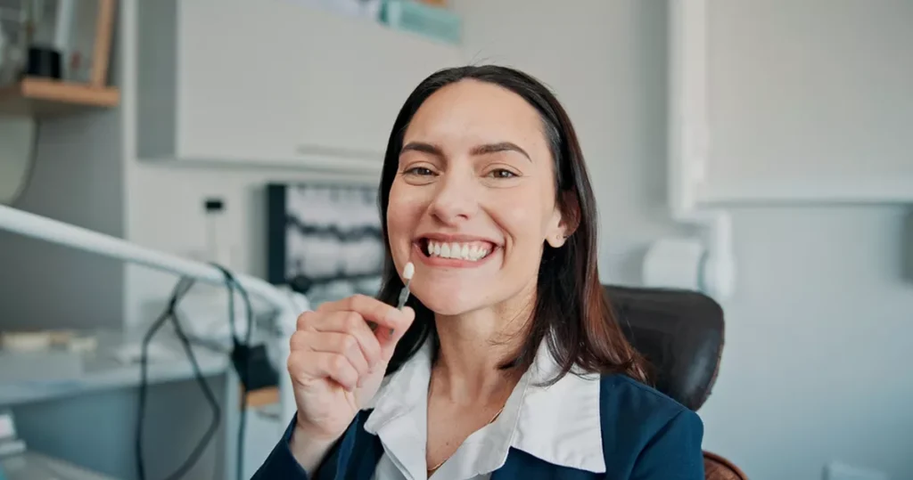 A smiling woman holding an implant.
