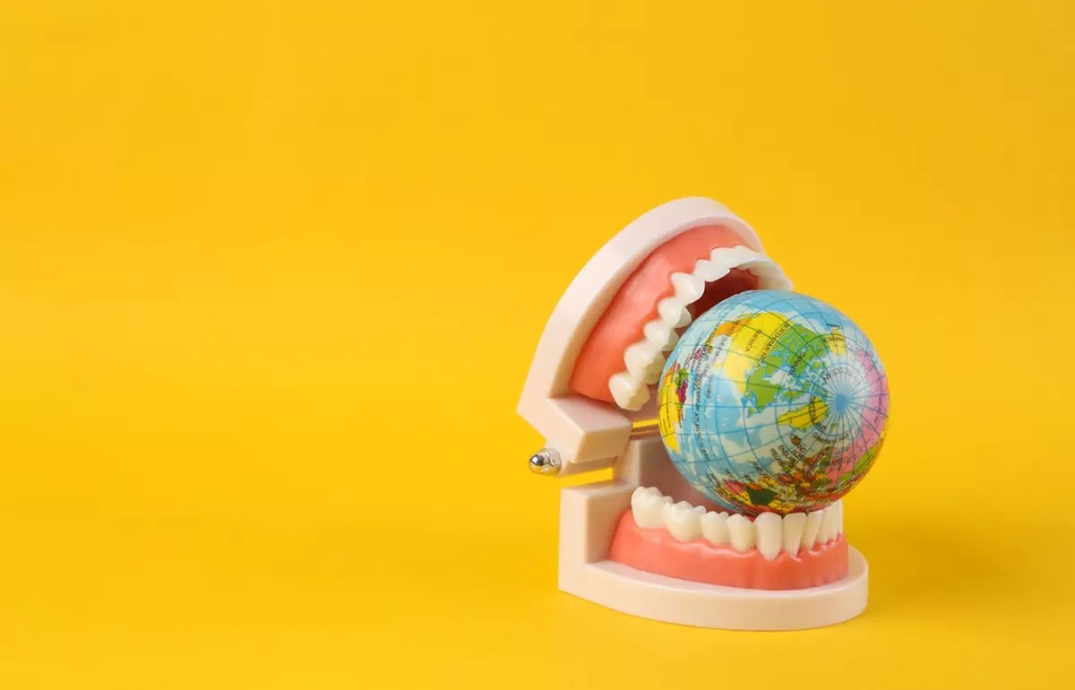 A model of a human jaw around a globe, representing dental tourism
