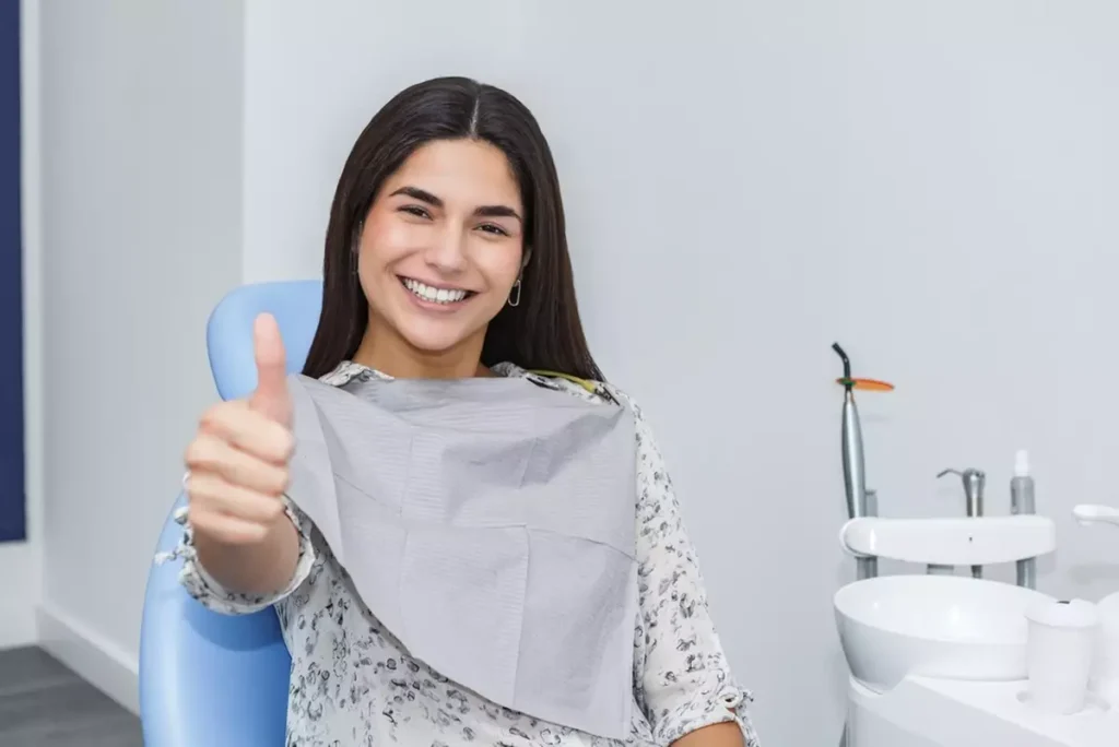 A woman giving a thumbs up in a dentist’s chair